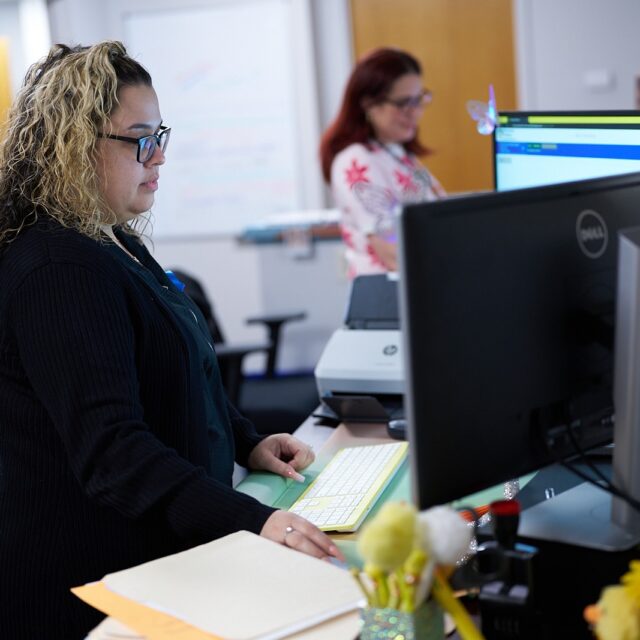 Office workers focusing on computer screens in a modern workspace.