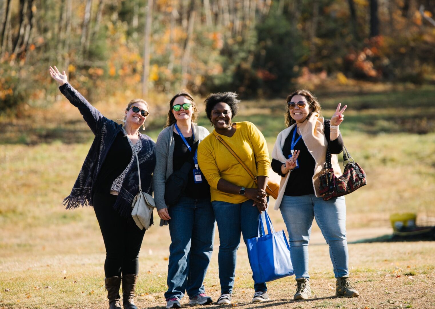 Four friends posing together outdoors with autumn trees in the background.