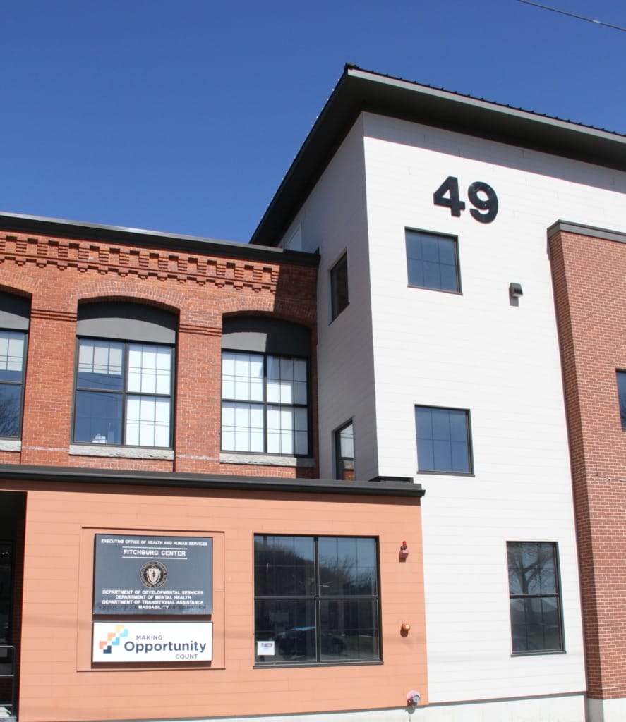 Red brick building with large windows and a sign reading "Making Opportunity Count" next to the entrance.
